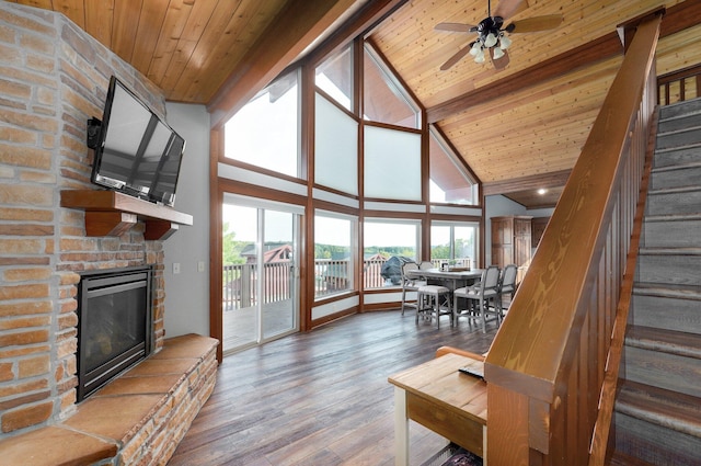 living room with beam ceiling, wood ceiling, a stone fireplace, high vaulted ceiling, and hardwood / wood-style flooring