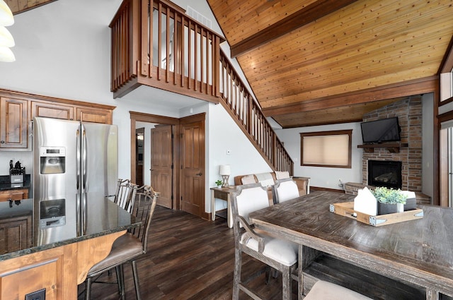 dining room featuring beamed ceiling, wood ceiling, dark wood-type flooring, high vaulted ceiling, and a fireplace