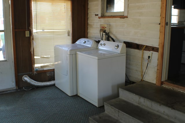 laundry room with wooden walls and washer and clothes dryer