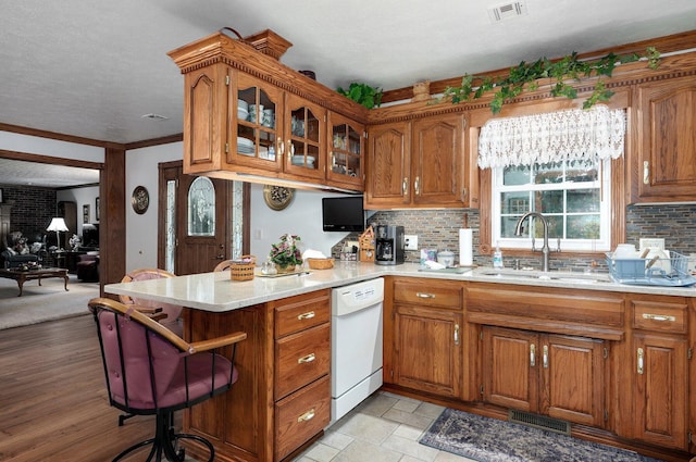 kitchen featuring ornamental molding, sink, dishwasher, an inviting chandelier, and light hardwood / wood-style floors