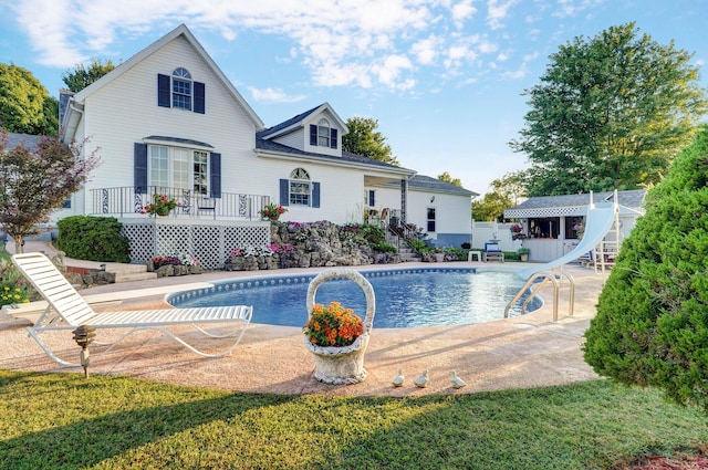 view of swimming pool featuring a deck, a lawn, and a water slide