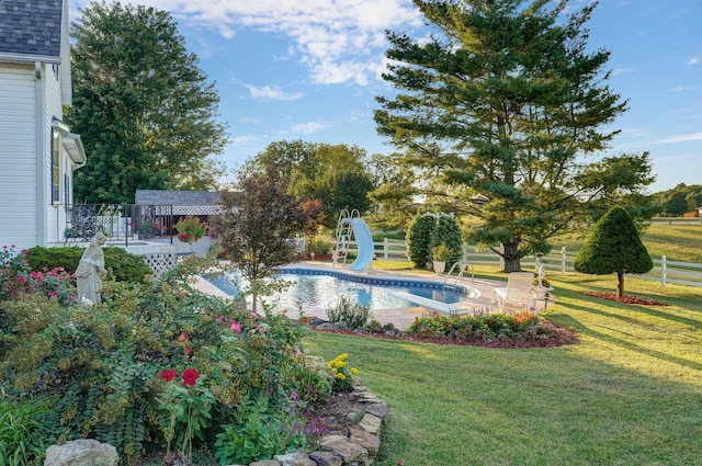 view of swimming pool with a yard, a water slide, and a patio area