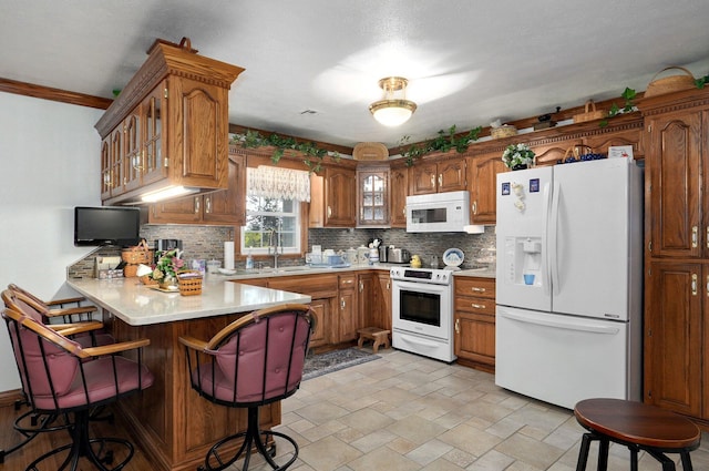 kitchen featuring tasteful backsplash, white appliances, sink, kitchen peninsula, and crown molding