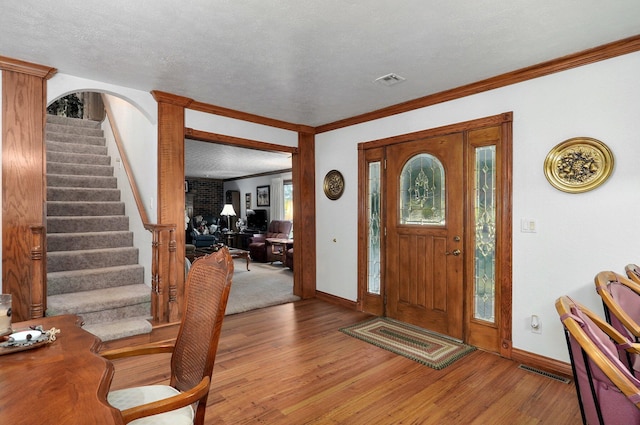 entryway featuring ornamental molding, a textured ceiling, and light hardwood / wood-style flooring