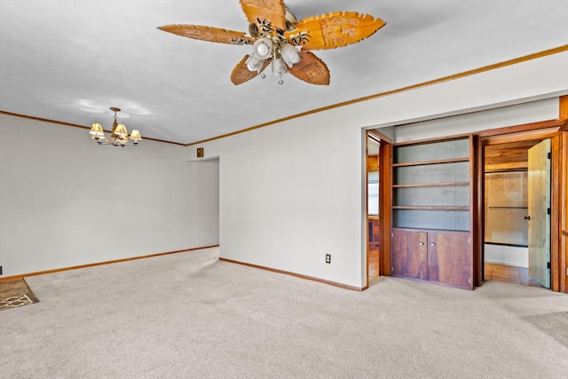 empty room featuring ceiling fan with notable chandelier, light carpet, and crown molding