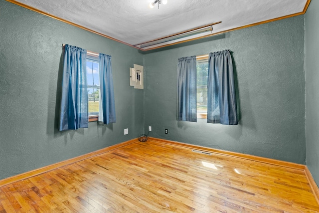 spare room featuring ornamental molding, hardwood / wood-style floors, and a textured ceiling