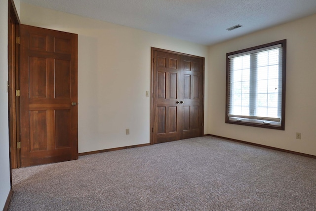 unfurnished bedroom with a closet, light colored carpet, and a textured ceiling