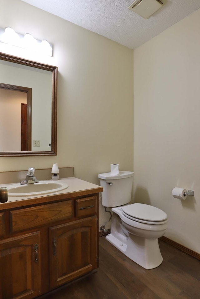 bathroom featuring wood-type flooring, vanity, toilet, and a textured ceiling