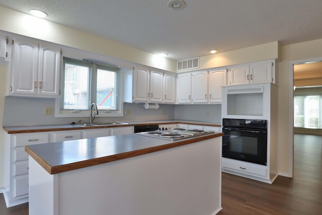 kitchen featuring sink, white cabinetry, black oven, a center island, and dark hardwood / wood-style flooring