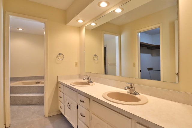 bathroom with tile patterned floors, vanity, and tiled bath