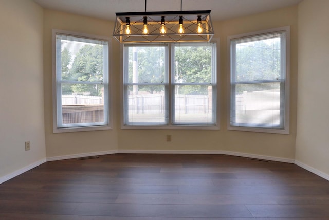 unfurnished dining area featuring dark wood-type flooring and a wealth of natural light