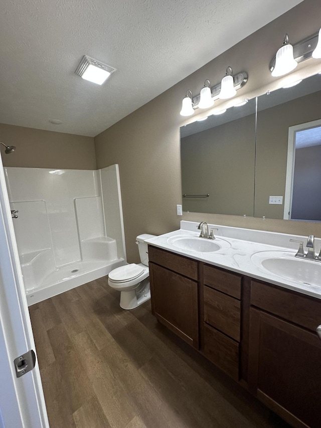 bathroom with vanity, toilet, a textured ceiling, walk in shower, and wood-type flooring