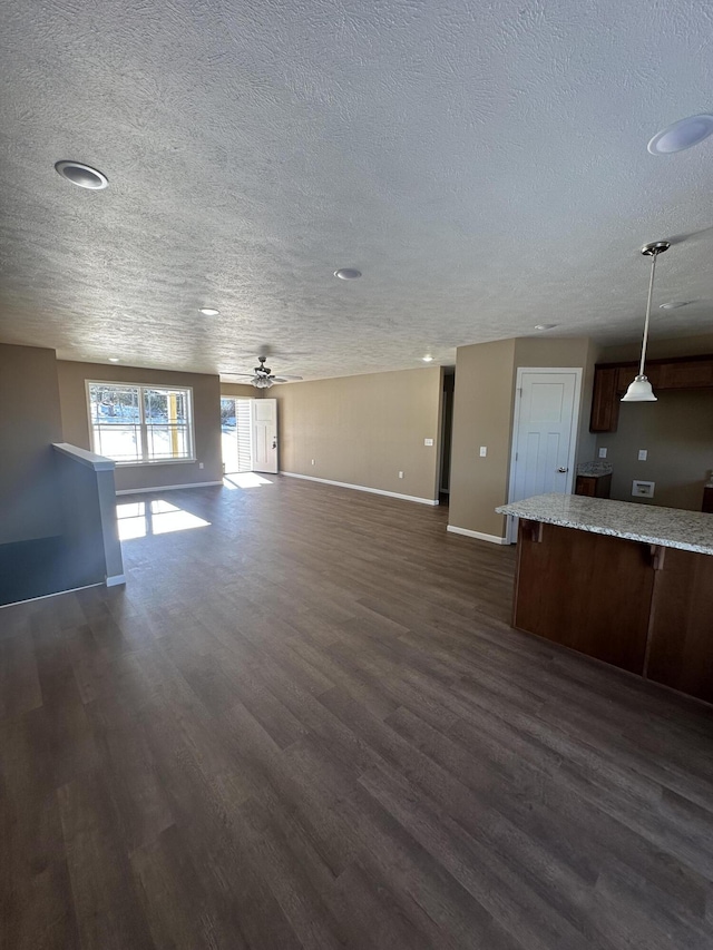 unfurnished living room with a textured ceiling, dark hardwood / wood-style flooring, and ceiling fan