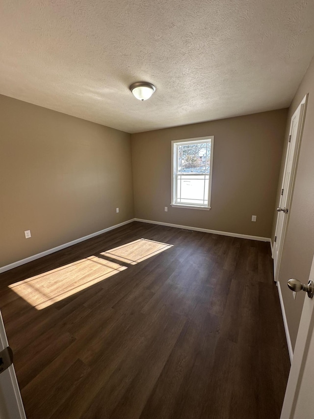 empty room with a textured ceiling and dark hardwood / wood-style floors