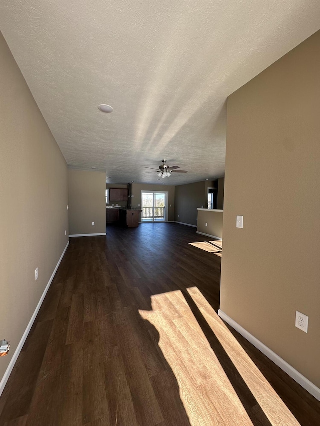 unfurnished living room with ceiling fan, dark wood-type flooring, and a textured ceiling