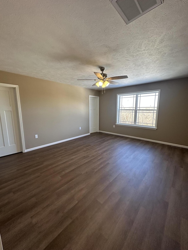 unfurnished room with ceiling fan, dark wood-type flooring, and a textured ceiling