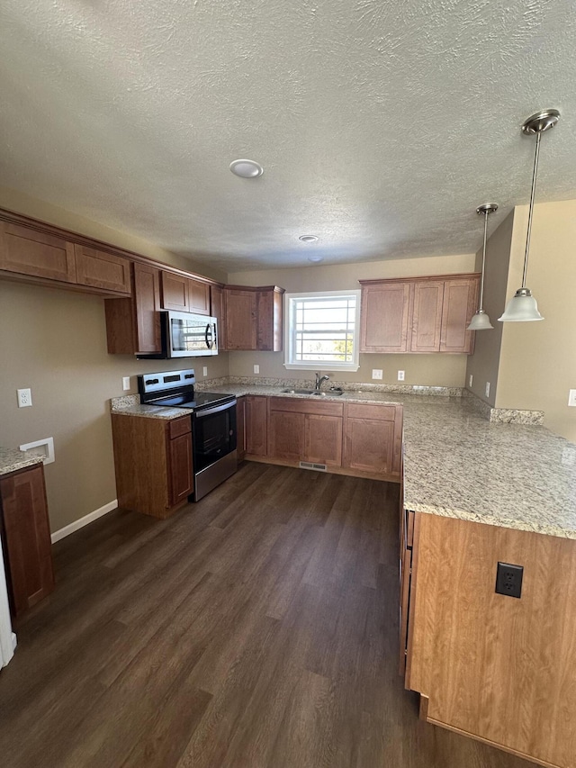 kitchen featuring kitchen peninsula, a textured ceiling, stainless steel appliances, pendant lighting, and dark hardwood / wood-style floors