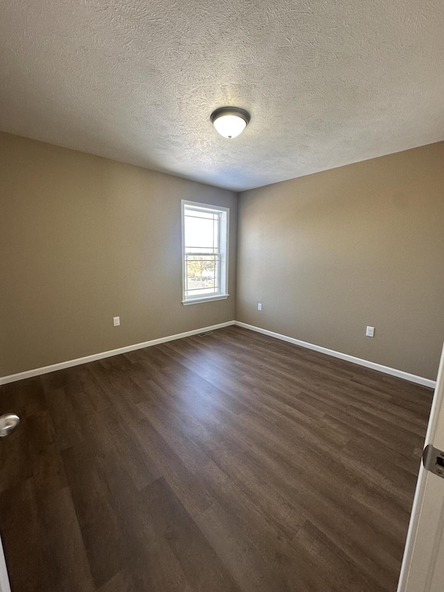 unfurnished room featuring dark wood-type flooring and a textured ceiling