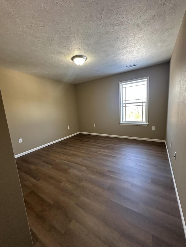 empty room featuring a textured ceiling and dark hardwood / wood-style floors