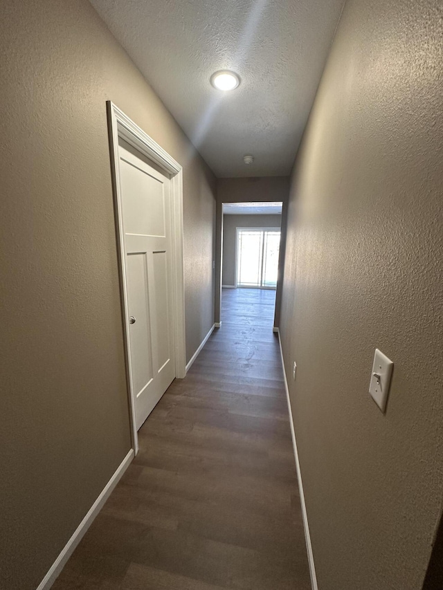 hall with dark hardwood / wood-style flooring and a textured ceiling