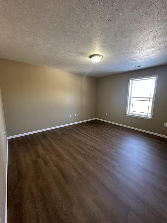 spare room with dark hardwood / wood-style flooring and a textured ceiling