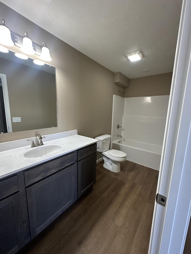 full bathroom featuring vanity, bathing tub / shower combination, hardwood / wood-style flooring, toilet, and a textured ceiling