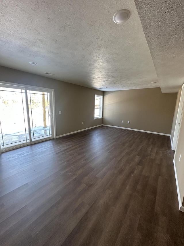 empty room with dark hardwood / wood-style floors and a textured ceiling