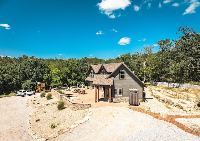 1326 Bald Eagle Dr, Galena, MO 65656 - view of front facade with a forest view, a patio area, a playground, stone siding, and dirt driveway