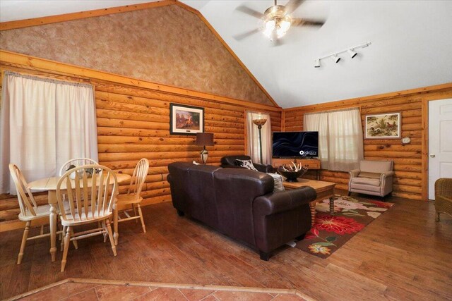 living room featuring high vaulted ceiling, ceiling fan, hardwood / wood-style floors, and rustic walls