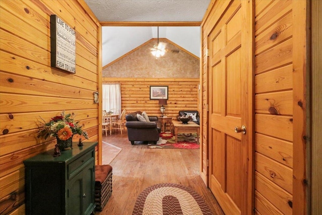 corridor with lofted ceiling, light hardwood / wood-style floors, ornamental molding, and a textured ceiling