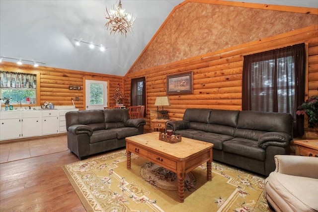 living room featuring log walls, high vaulted ceiling, light hardwood / wood-style floors, and rail lighting