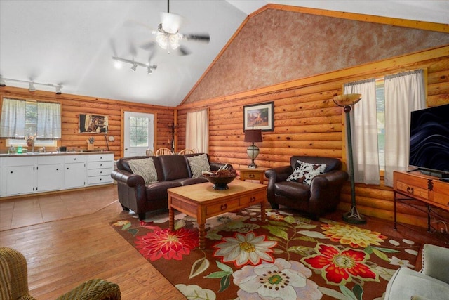 living room featuring ceiling fan, light hardwood / wood-style flooring, high vaulted ceiling, log walls, and rail lighting