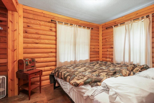 bedroom featuring multiple windows, rustic walls, dark hardwood / wood-style floors, and a textured ceiling