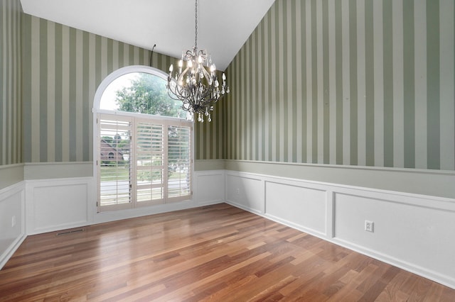 unfurnished dining area featuring wood-type flooring and a chandelier