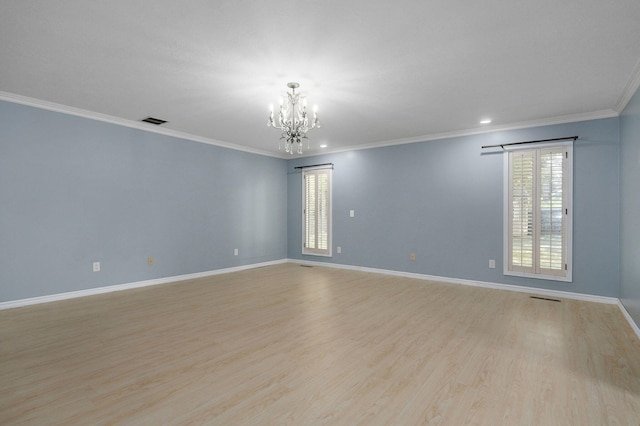 empty room featuring an inviting chandelier, light wood-type flooring, and crown molding