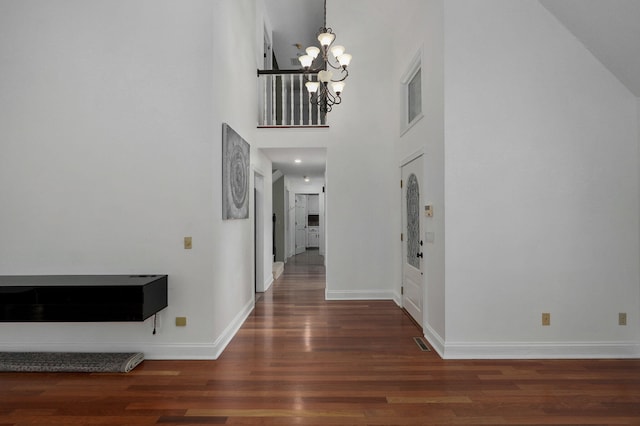 foyer featuring dark wood-type flooring, a high ceiling, and an inviting chandelier