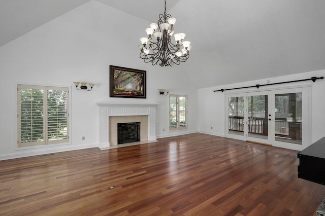 unfurnished living room with a notable chandelier, high vaulted ceiling, a wealth of natural light, and dark hardwood / wood-style flooring