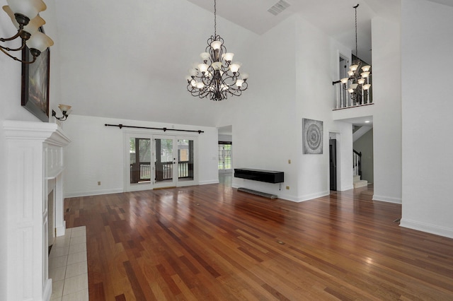 unfurnished living room featuring wood-type flooring, high vaulted ceiling, and an inviting chandelier