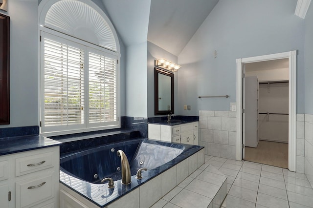 bathroom featuring tile patterned floors, a relaxing tiled tub, vaulted ceiling, and vanity