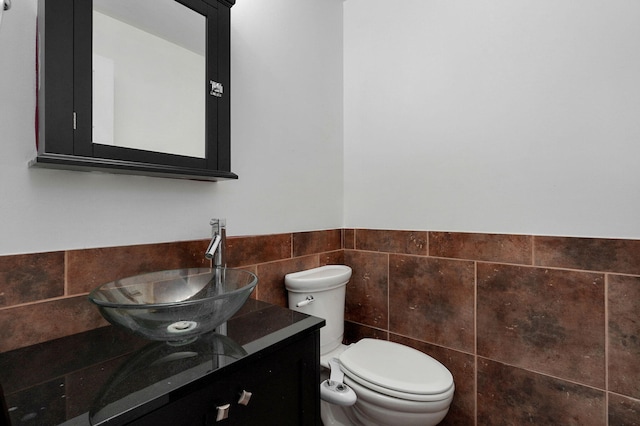 bathroom featuring tile walls, vanity, and toilet