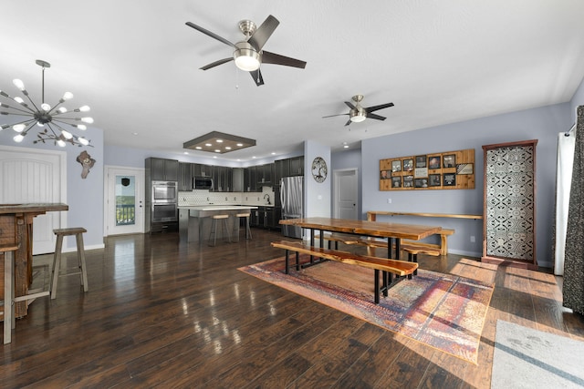 dining space featuring dark wood-type flooring and ceiling fan with notable chandelier