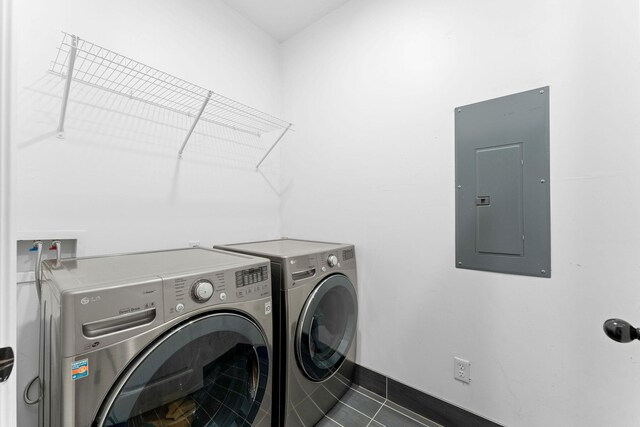 clothes washing area featuring electric panel, dark tile patterned floors, and washing machine and clothes dryer