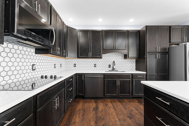 kitchen with dark brown cabinets, dark wood-type flooring, sink, decorative backsplash, and appliances with stainless steel finishes