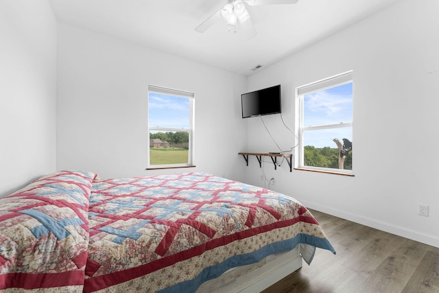 bedroom featuring hardwood / wood-style flooring, multiple windows, and ceiling fan