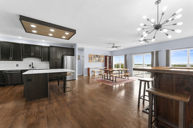 kitchen with a kitchen island, dark hardwood / wood-style floors, stainless steel appliances, pendant lighting, and a kitchen breakfast bar