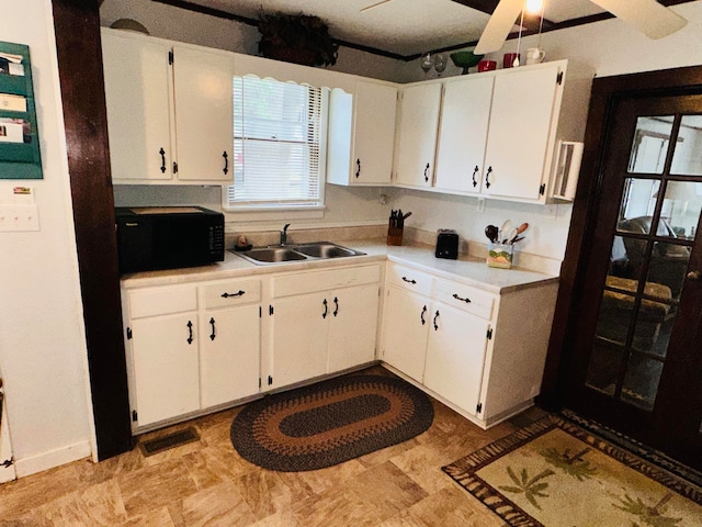 kitchen featuring ceiling fan, sink, and white cabinets