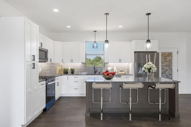 kitchen with a center island, white cabinetry, stainless steel appliances, and dark wood-type flooring