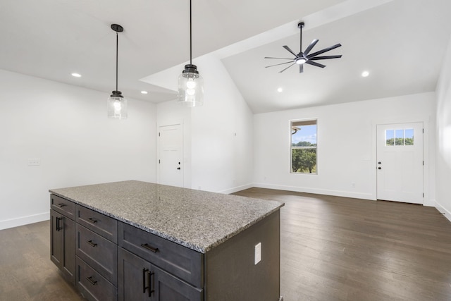 kitchen featuring dark hardwood / wood-style flooring, light stone countertops, hanging light fixtures, and vaulted ceiling