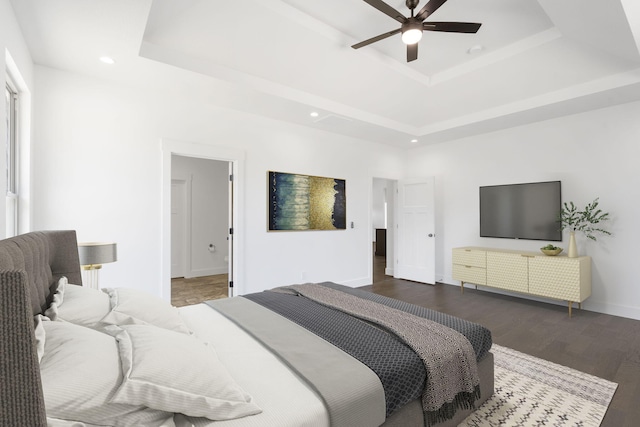 bedroom featuring ceiling fan, dark hardwood / wood-style flooring, and a tray ceiling