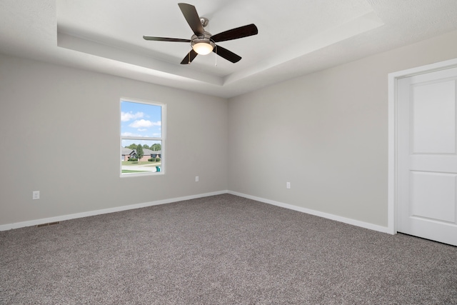 empty room featuring a raised ceiling and carpet